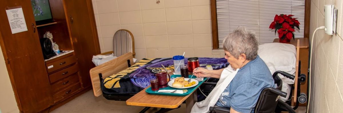 73 year old woman enjoying a supper meal in a nursing home because of a stroke