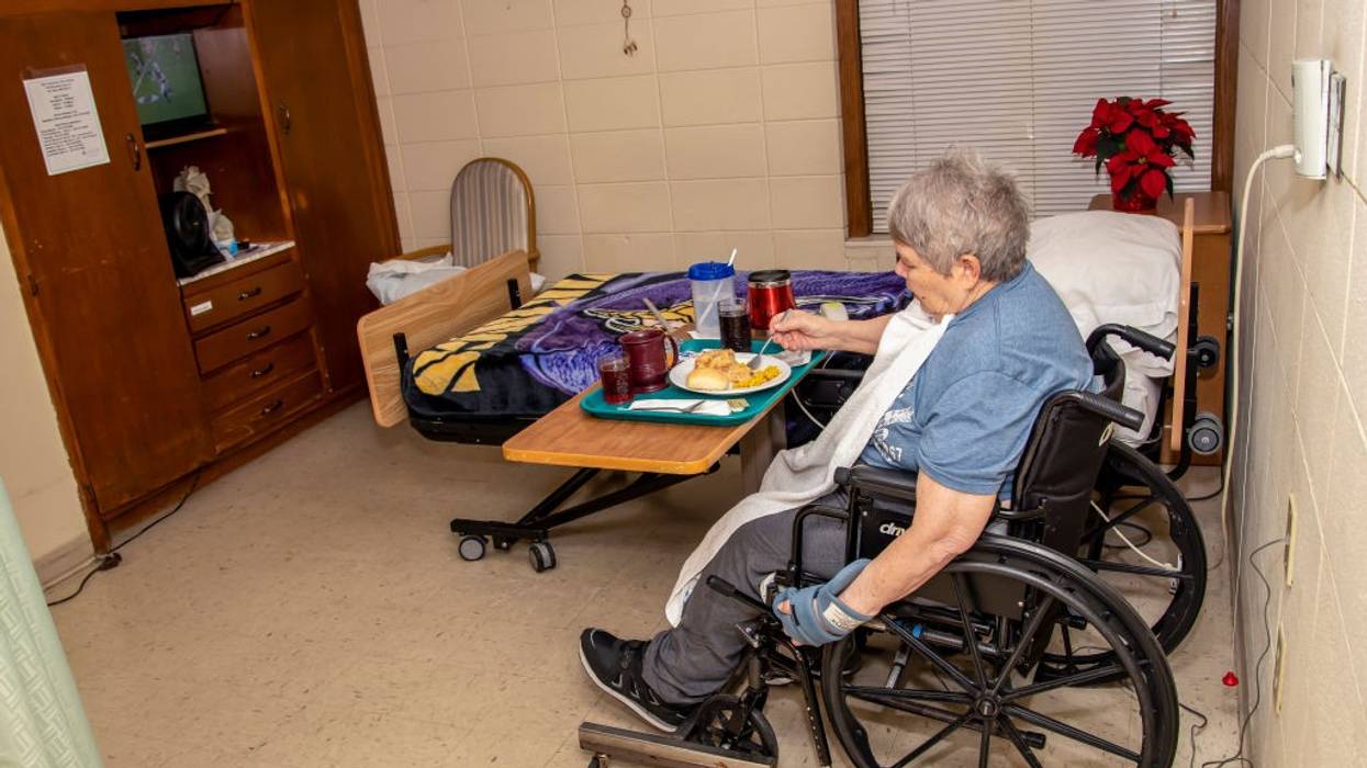 73 year old woman enjoying a supper meal in a nursing home because of a stroke