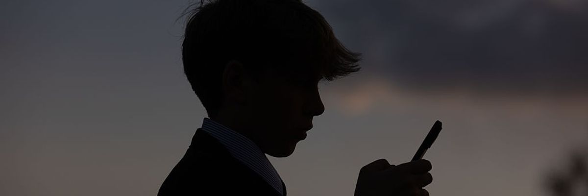 A 13-year-old boy looks at an iPhone