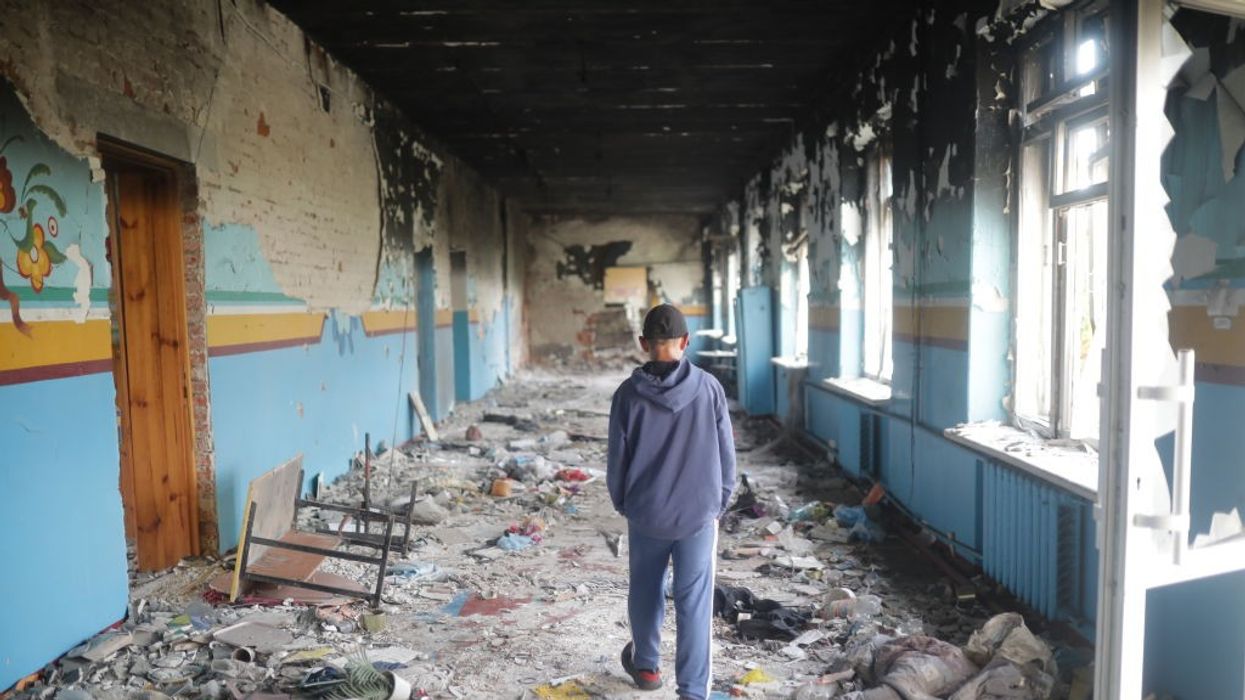 A 13-year-old walks away from the camera through a bombed high school hallway in Ukraine.