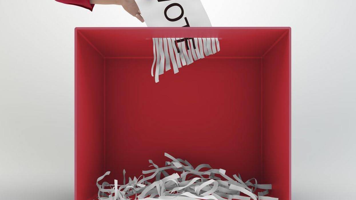 A ballot is shredded as a voter puts it in a voting box.