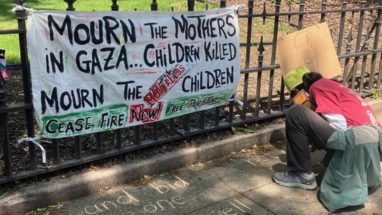 A banner on a fence reads, "Mourn the mothers in Gaza... children killed. Mourn the children."