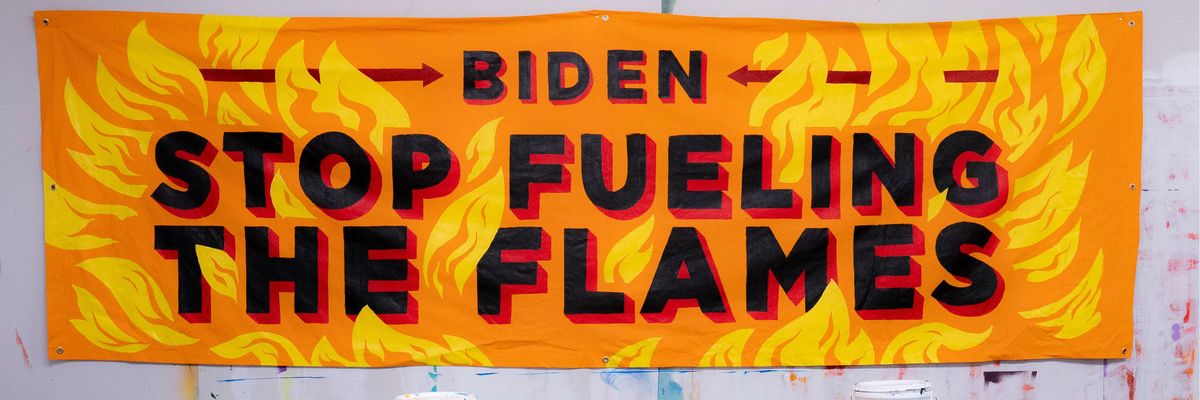 A banner painted with flames saying, "Biden, stop fueling the flames."