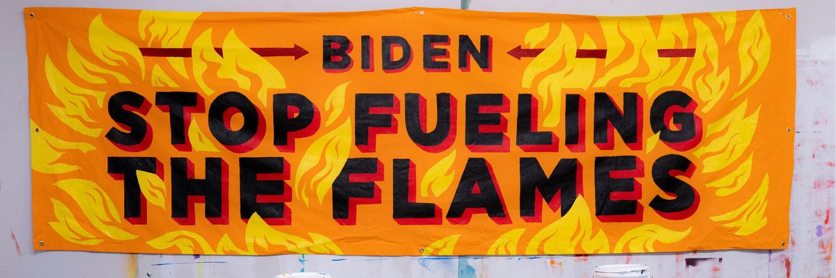 A banner painted with flames saying, "Biden, stop fueling the flames."