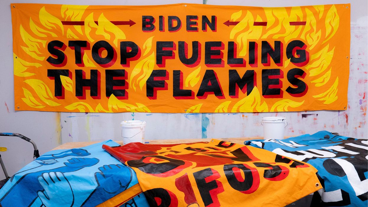 A banner painted with flames saying, "Biden, stop fueling the flames."