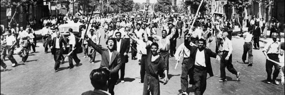 A black-and-white photo of Iranians protesting down a wide street. 