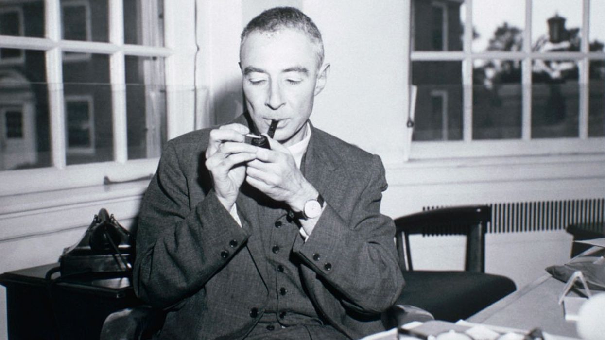 A black-and-white photo of J. Robert Oppenheimer smoking a pipe.