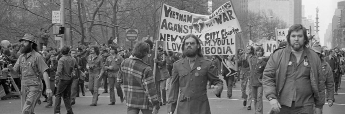 A black-and-white photo of marchers carrying a Vietnam Veterans Against the War sign.