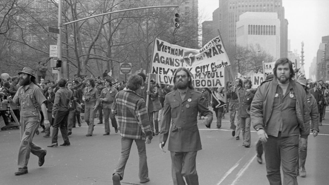 A black-and-white photo of marchers carrying a Vietnam Veterans Against the War sign.