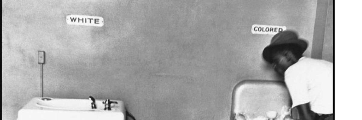 A Black man drinks at a "Colored" water fountain during widespread Jim Crow laws