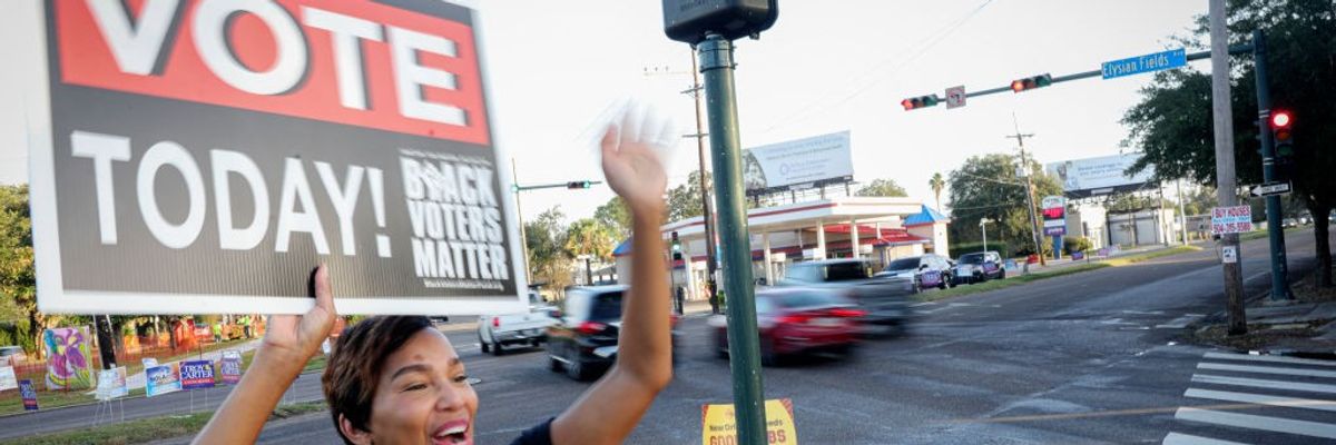 A Black woman holds a sign saying "Vote Today"
