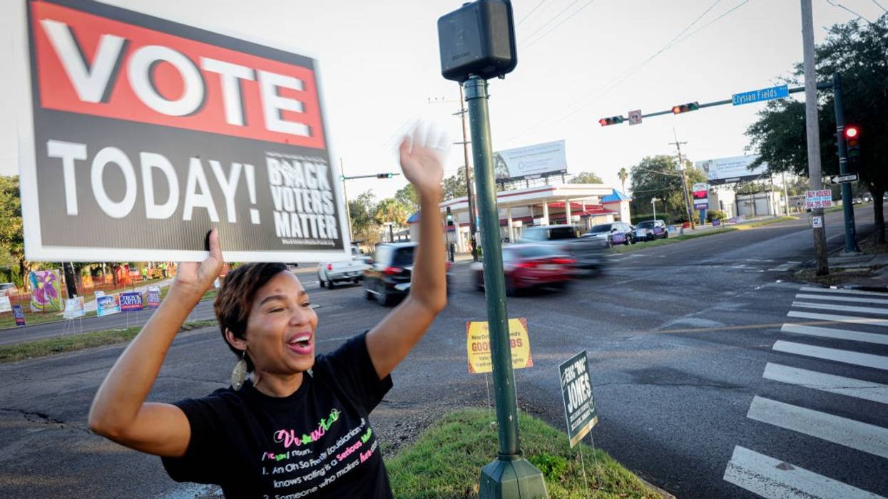 A Black woman holds a sign saying "Vote Today"