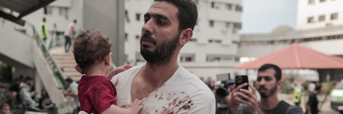 A bloodied Palestinian man and his baby arrive at Gaza hospital