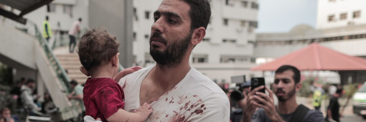 A bloodied Palestinian man and his baby arrive at Gaza hospital