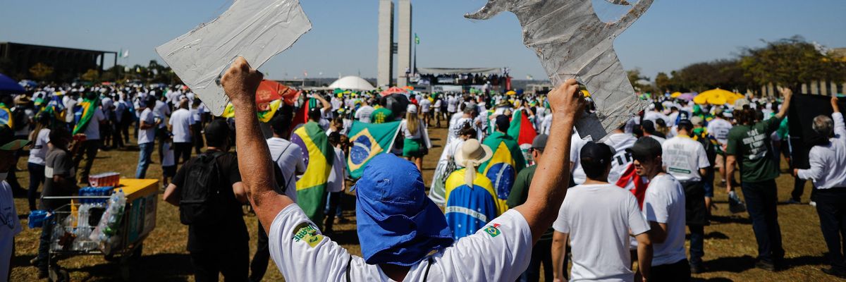 A Bolsonaro supporter holds two signs shaped like handguns at rally