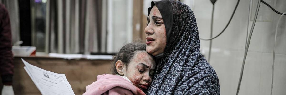 A bombed and bloodied Palestinian mother and daughter share a tearful embrace in Gaza