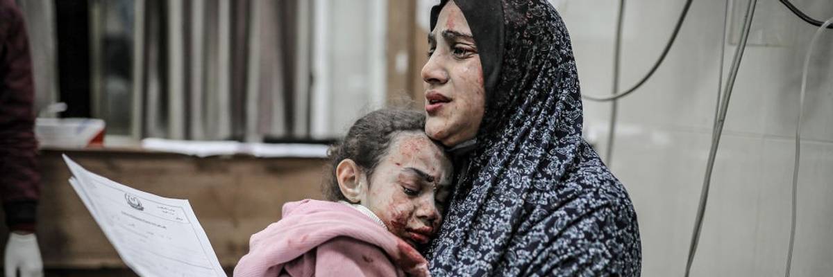 A bombed and bloodied Palestinian mother and daughter share a tearful embrace in Gaza
