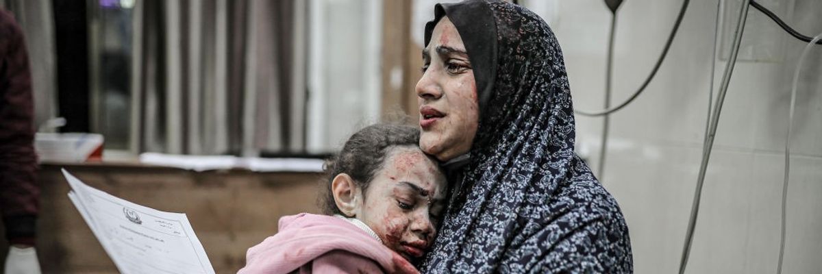 A bombed and bloodied Palestinian mother and daughter share a tearful embrace in Gaza