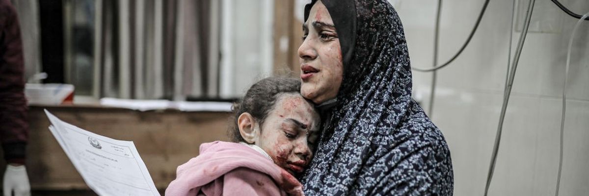 A bombed and bloodied Palestinian mother and daughter share a tearful embrace in Gaza