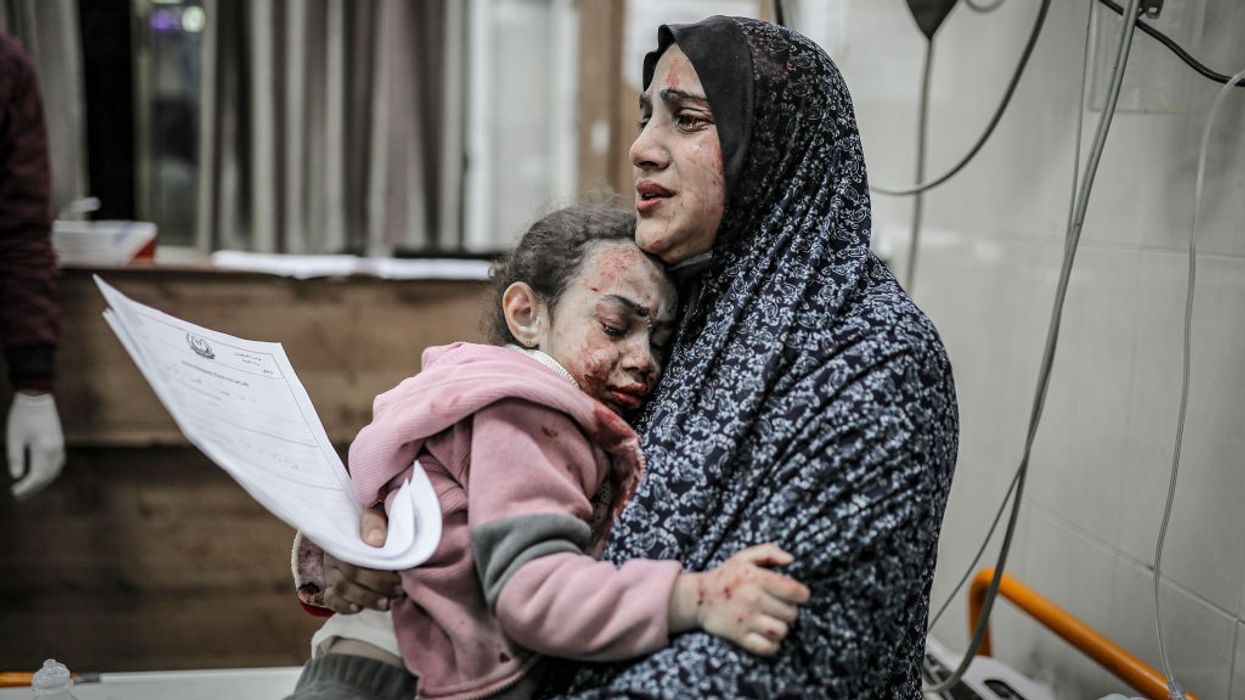 A bombed and bloodied Palestinian mother and daughter share a tearful embrace in Gaza
