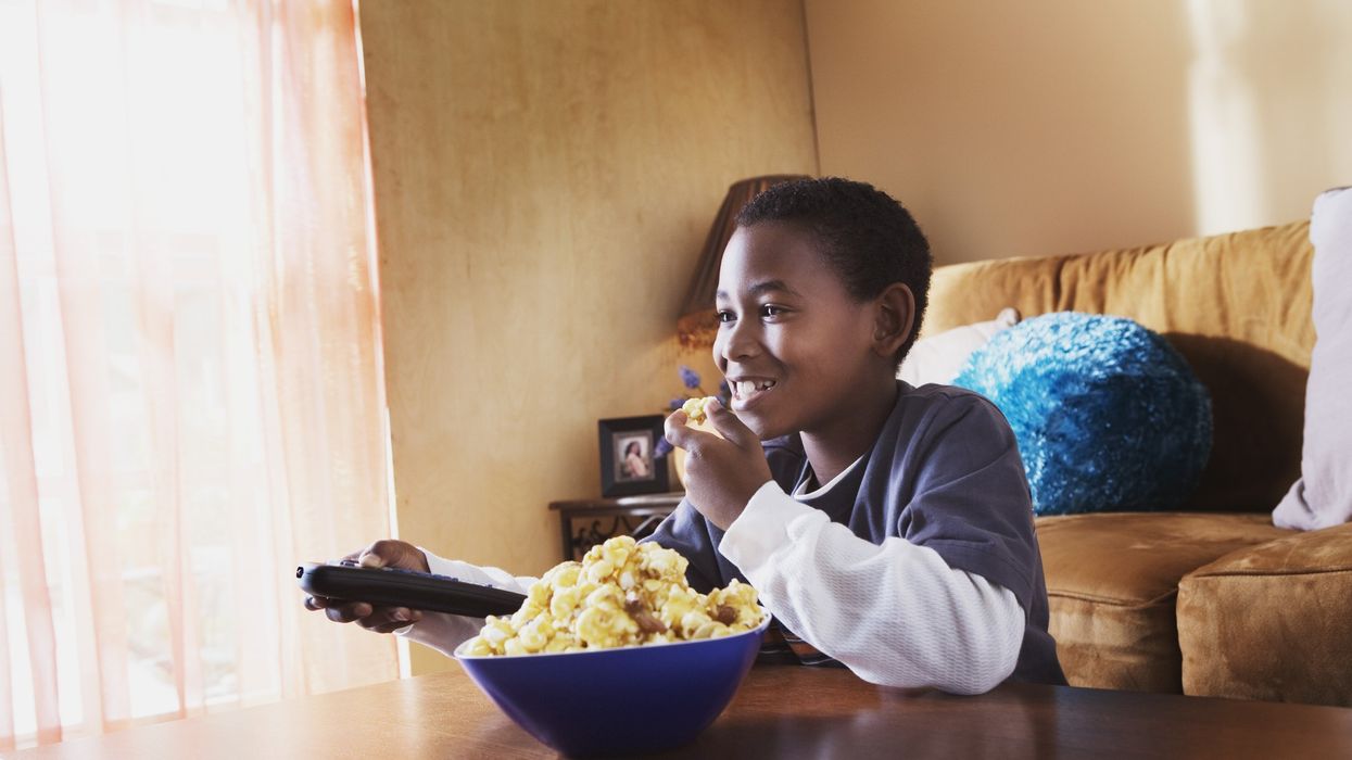 a boy eats popcorn while watching tv