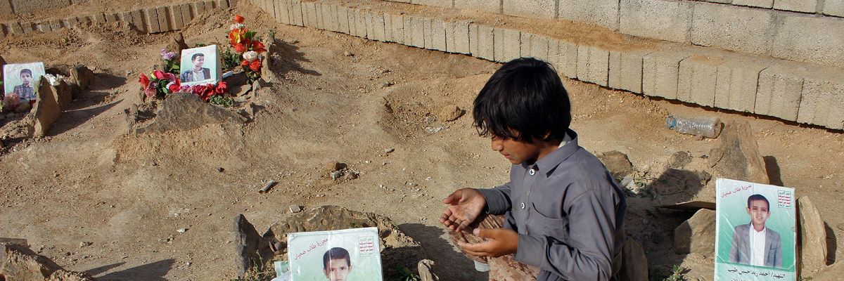 A boy kneels by the graves of two boys killed by an airstrike in Yemen