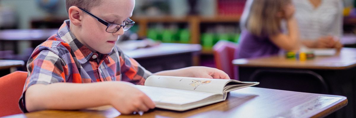 A boy reads at a desk in an elementary school.