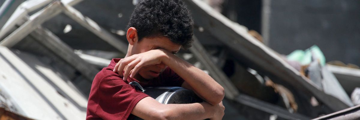 A boy sits with an empty pot at a charity distribution in Jabalia in the northern Gaza Strip