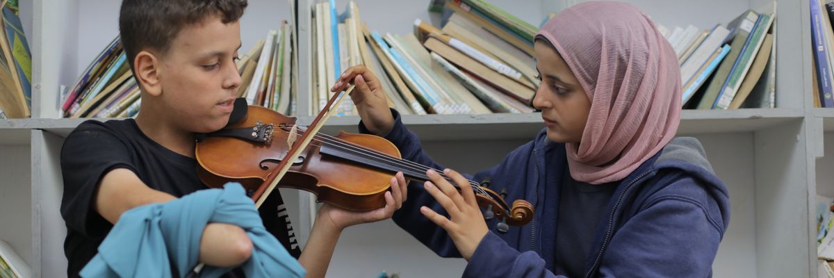 A boy with an amputated arm receives violin lessons in Gaza.