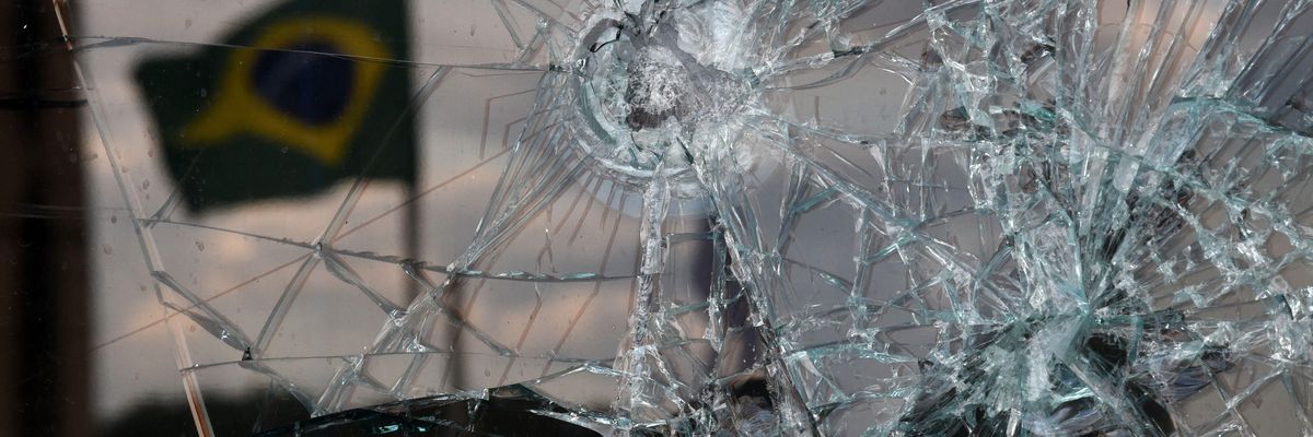 A Brazilian flag is reflected on a broken window of the Supreme Court building in Brasília