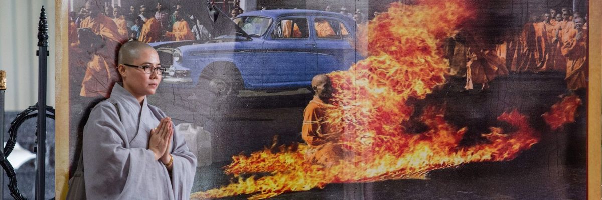 A Buddhist monk stands next to a banner showing Thick Quang Duc's 1963 self-immolation.