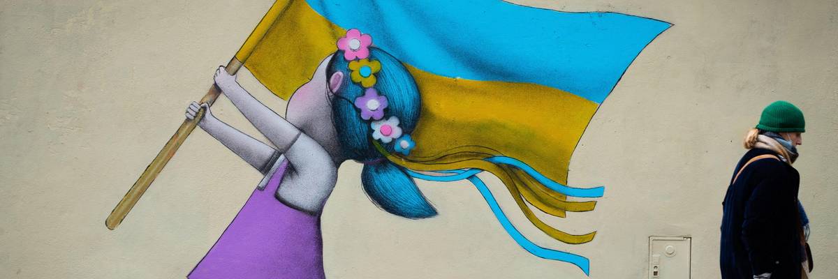 A bystander walks past a fresco by street artist Seth depicting a girl with a Ukrainian flag walking on tanks in Paris on March 1, 2022.