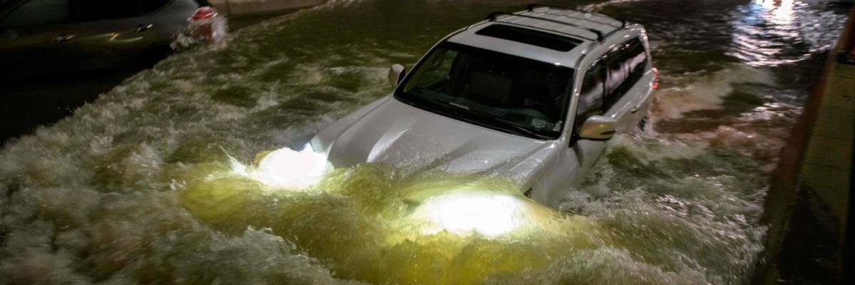 A car drives on a flooded street in New York Cty.