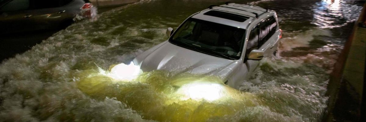 A car drives on a flooded street in New York Cty.