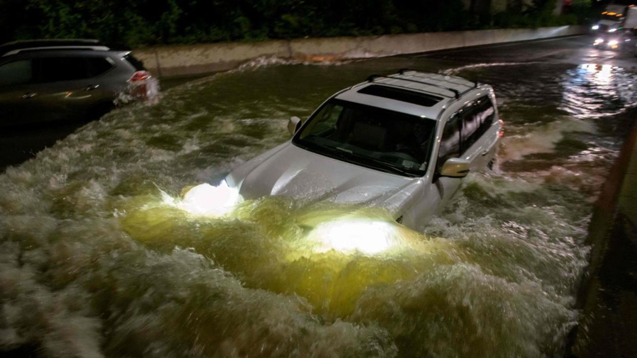 A car drives on a flooded street in New York Cty.