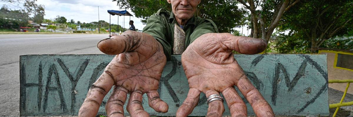 A charcoal seller in Cuba shows empty hands.