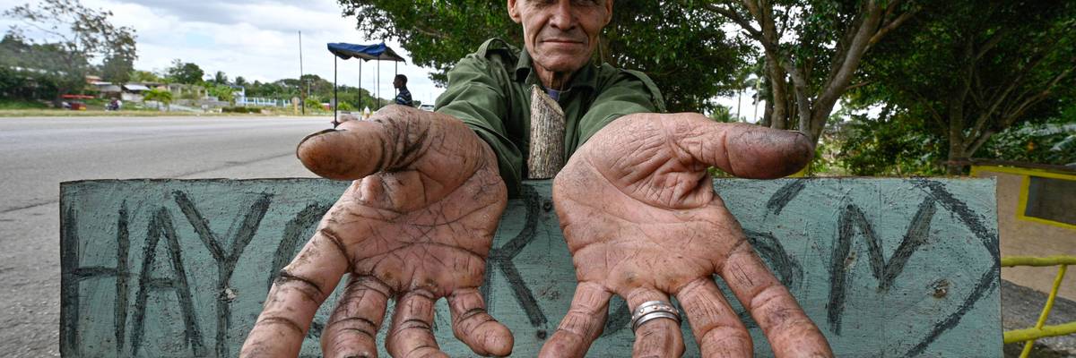 A charcoal seller in Cuba stretches out empty hands.