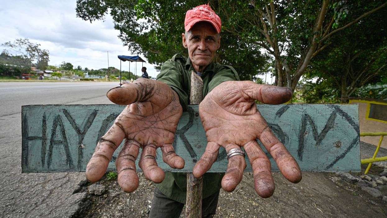 A charcoal seller in Cuba stretches out empty hands.