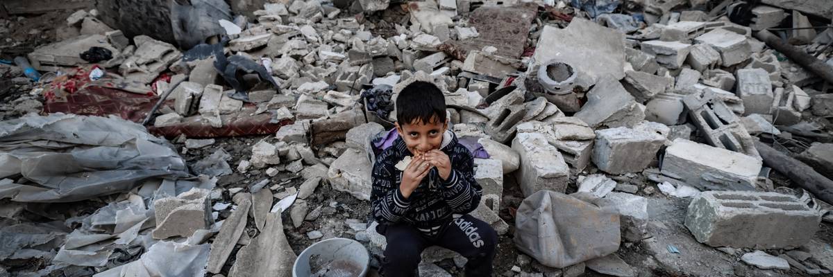 A child eats amid the rubble of destroyed buildings following Israeli bombardment in Rafah