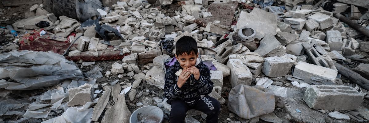 A child eats amid the rubble of destroyed buildings following Israeli bombardment in Rafah