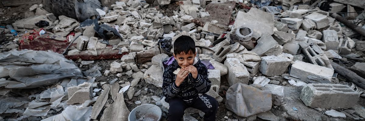  A child eats amid the rubble of destroyed buildings following Israeli bombardment in Rafah 