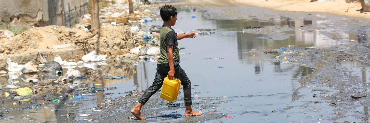 A child goes to get clean water on a street flooded with leaked sewage