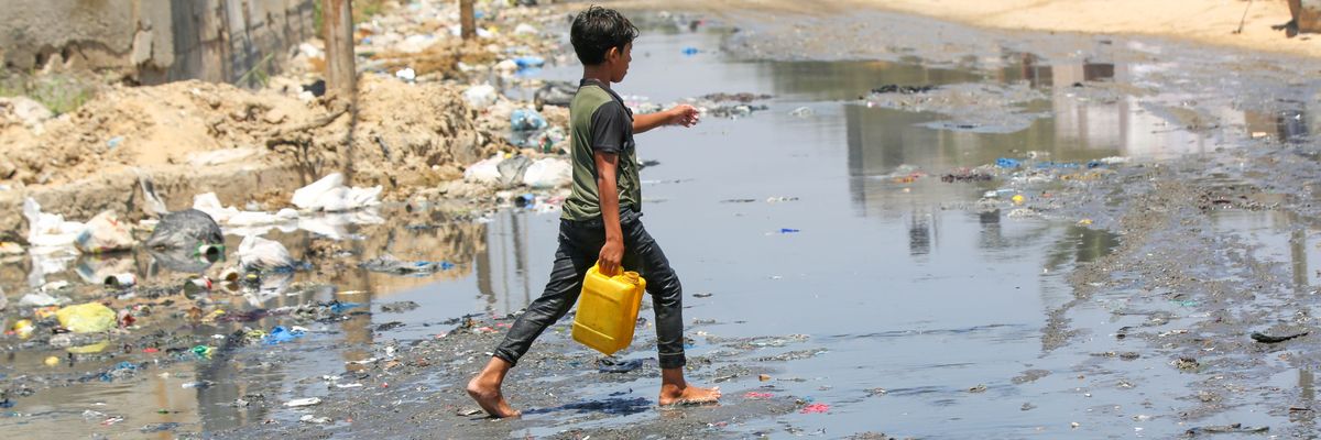 A child goes to get clean water on a street flooded with leaked sewage