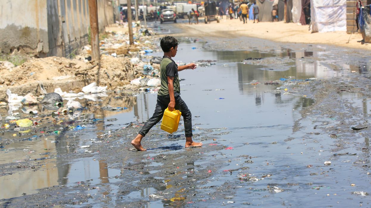 A child goes to get clean water on a street flooded with leaked sewage