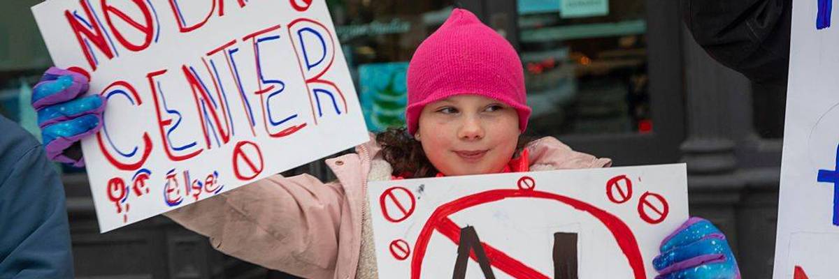 A child holds up a No Data Center sign.