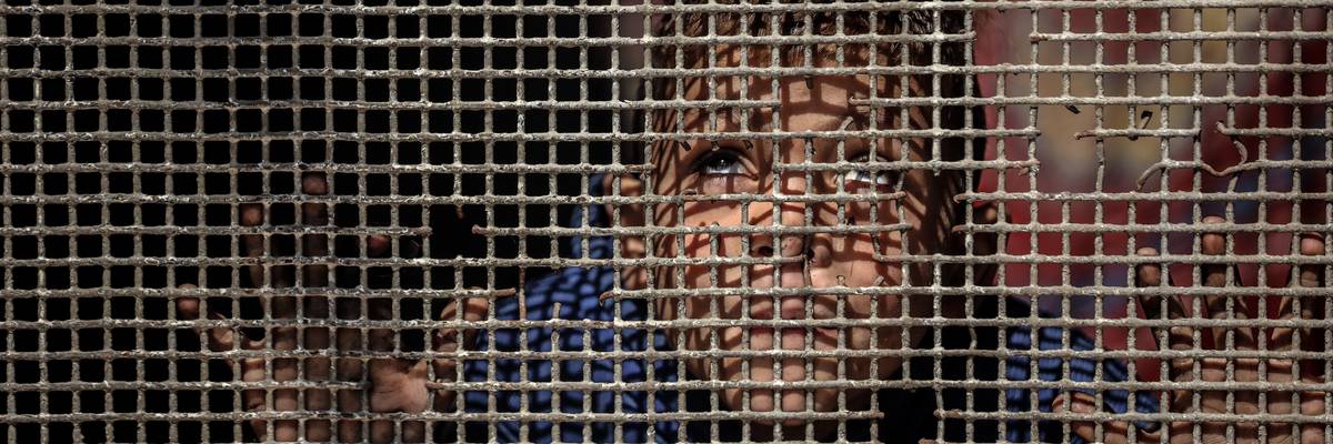 A child looks through a fence in Gaza.
