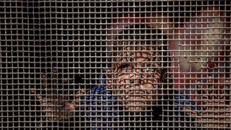 A child looks through a fence in Gaza.
