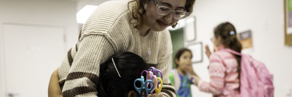 A child of immigrants hugs a teacher following "homework club" at a community center