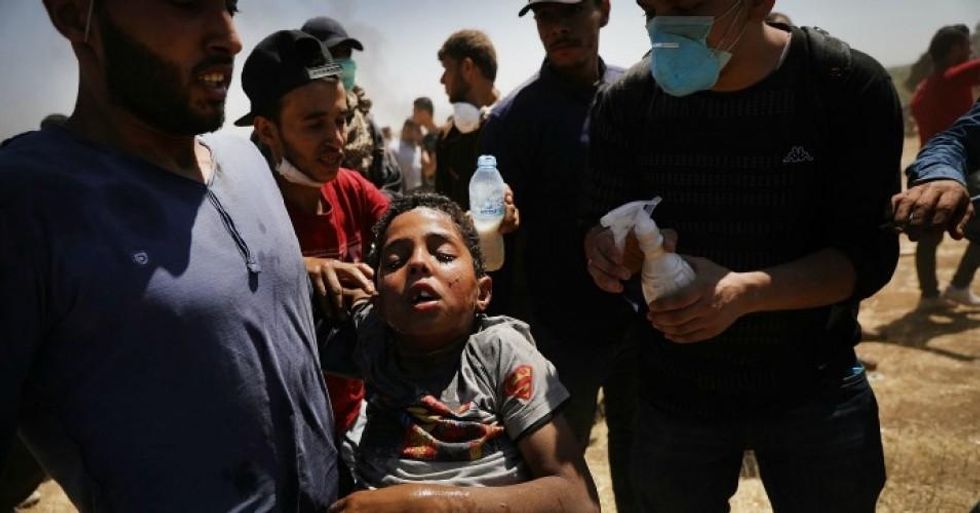 A child overcome by tear gas is rushed to medics at the border fence with Israel as mass demonstrations continue on May 14, 2018 in Gaza City, Gaza. Israeli soldiers killed at least 41 Palestinians and wounded over a thousand as the demonstrations coincided with the controversial opening of the U.S. Embassy in Jerusalem. This marks the deadliest day of violence in Gaza since 2014. (Photo: Spencer Platt/Getty Images)