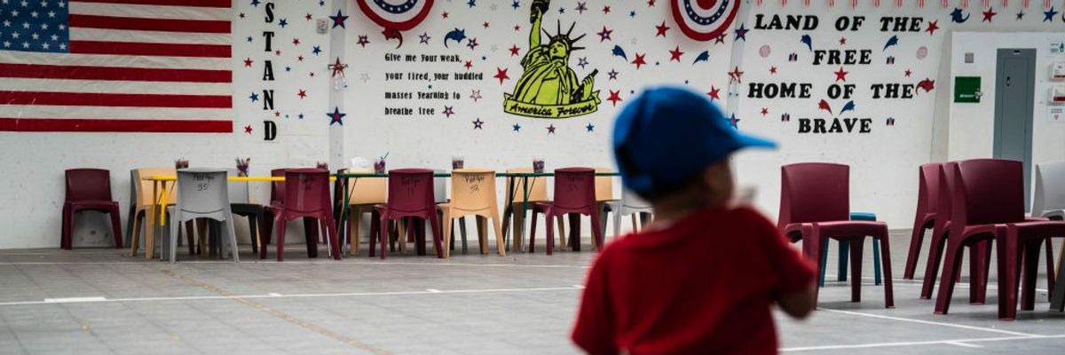 A child plays in front of patriotic phrases and symbols in an ICE lockup